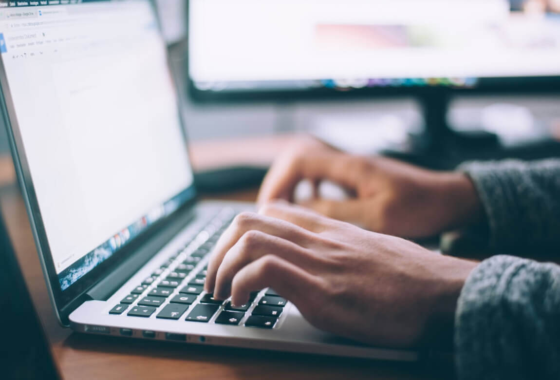 LinkGraph’s editorial team typing on a laptop and creating blog content to improve site authority and on-page optimization