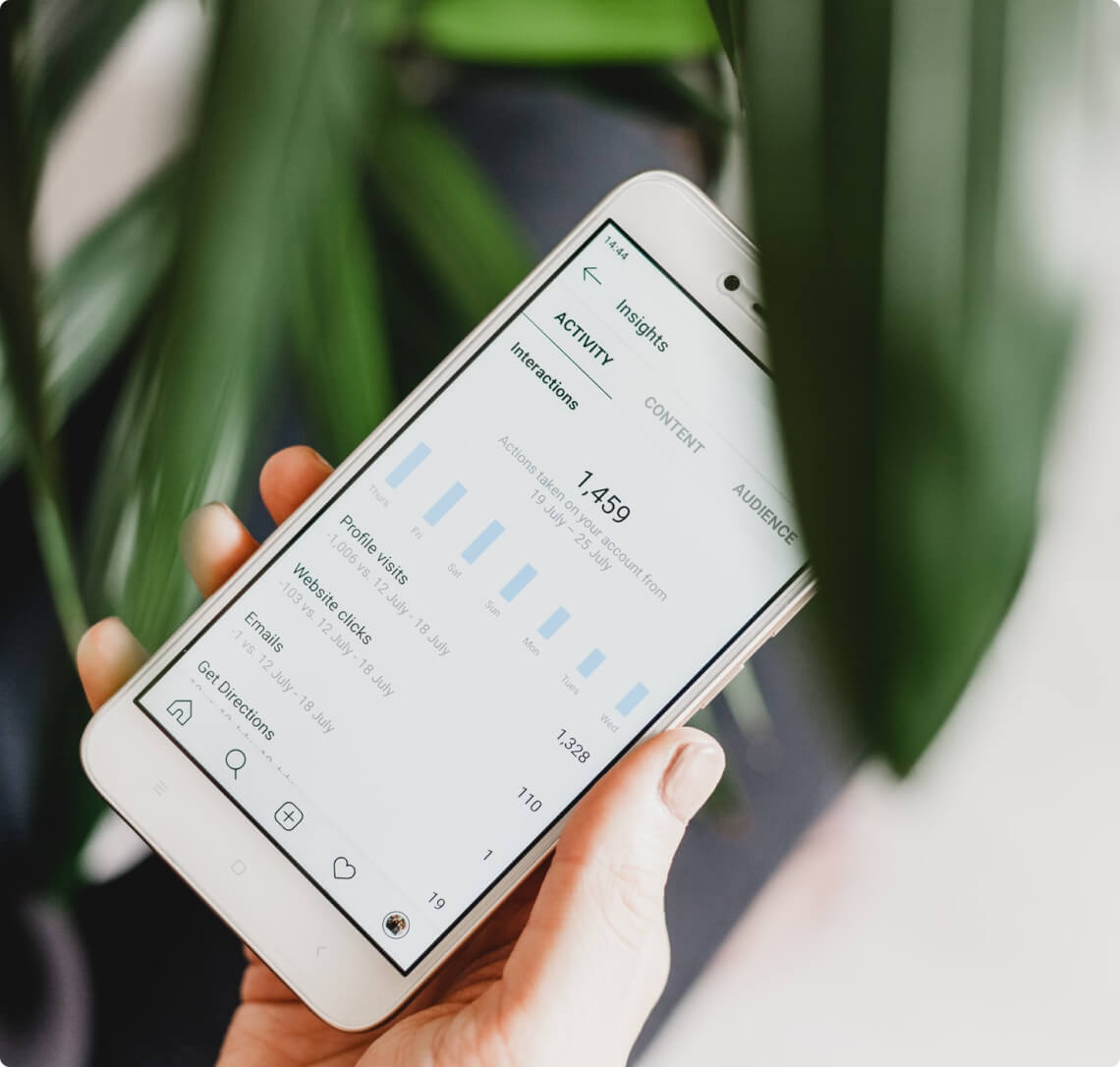 A person holding a smartphone with a plant on it while engaging in social media advertising.