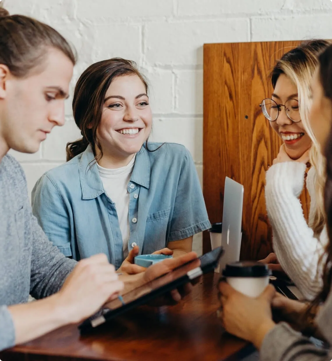 group of young professionals having a casual team meeting at a café with digital devices