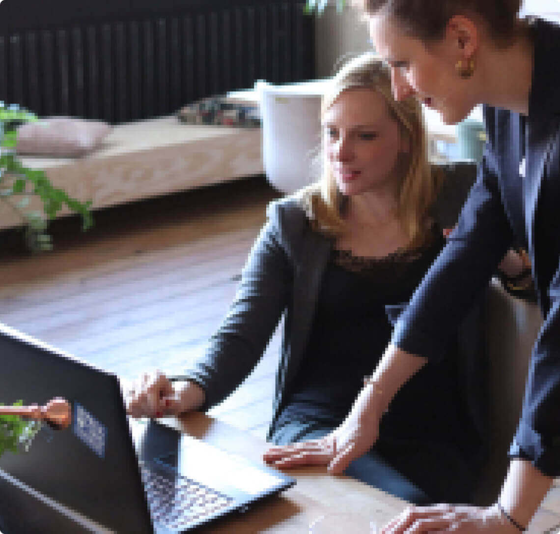 Two women optimizing a laptop.