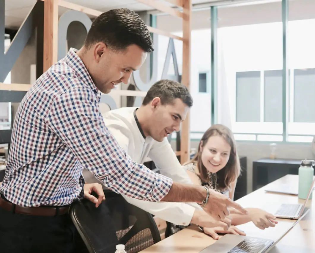 A group of people creating an infographic on a laptop in an office.