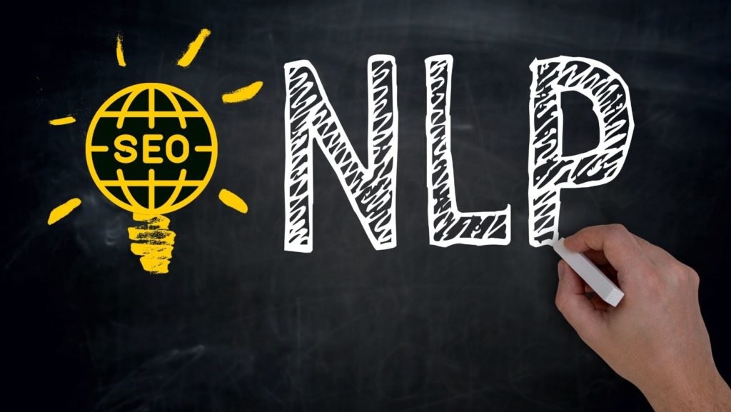 A hand drawing the word NLP on a blackboard for Google.