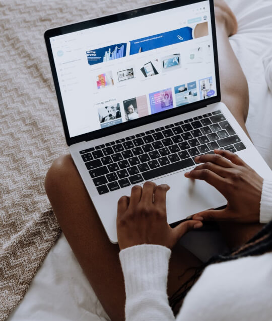 A woman utilizing a laptop for technical SEO services on a bed.