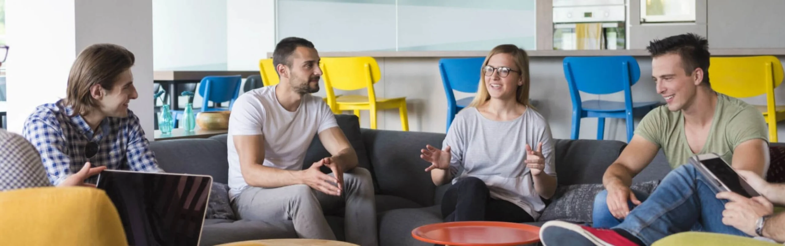 A group of co-workers happily discussing work while sitting on a couch.
