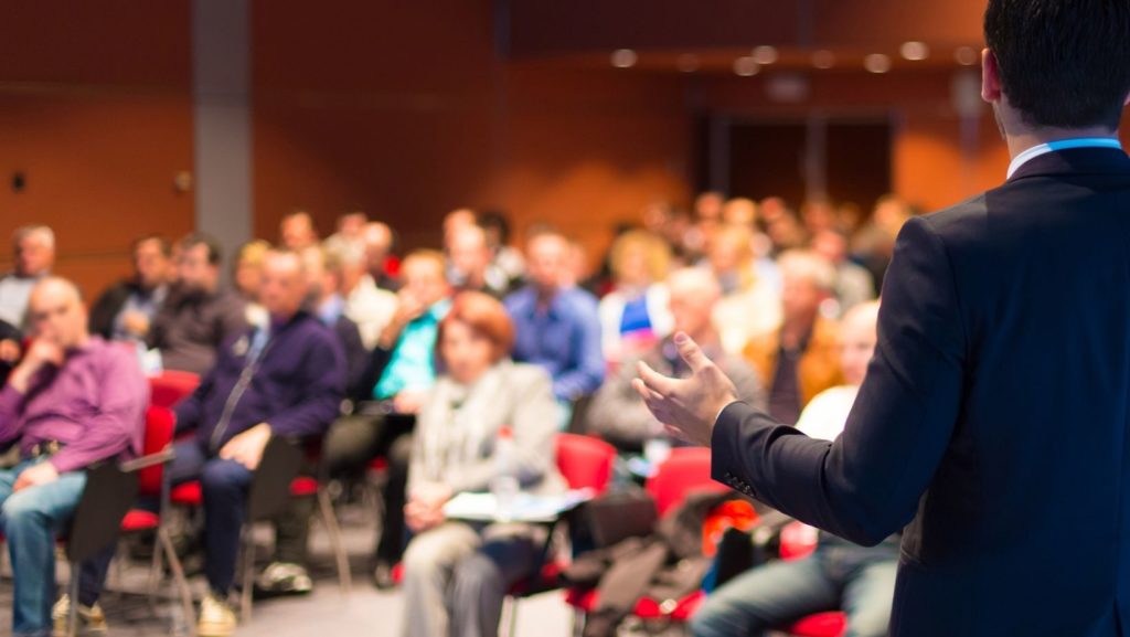 A man is presenting to an audience, focusing on an SEO checklist.