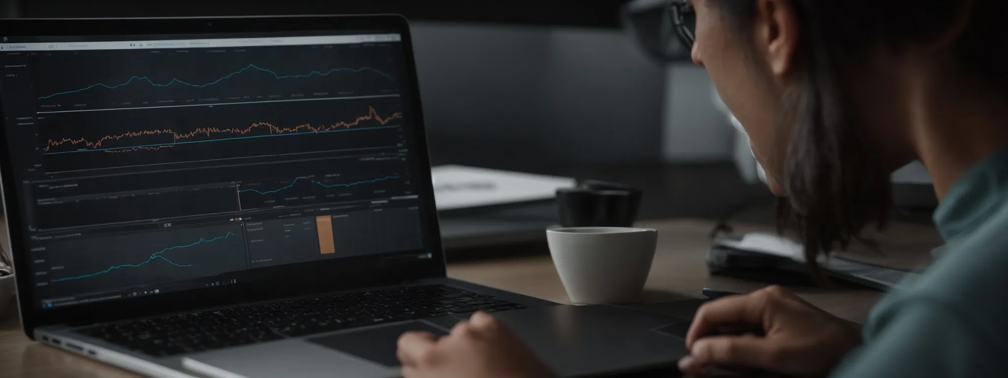a person working on a laptop with graphs and performance charts on the screen.